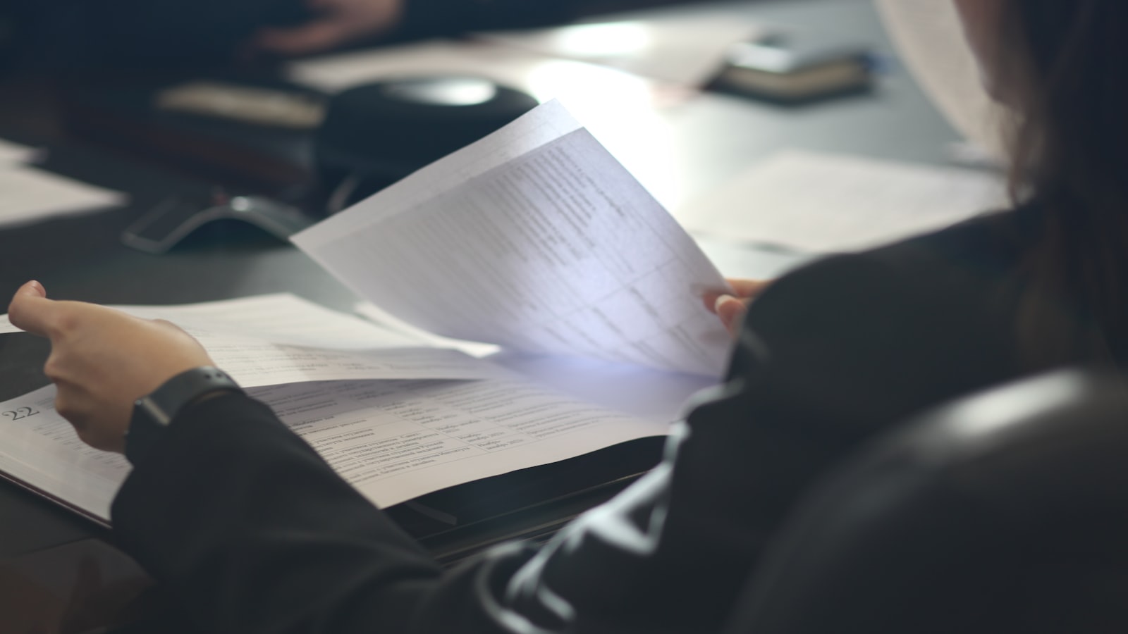 A woman sitting at a table reading a paper — photo by Anastassia Anufrieva on Unsplash