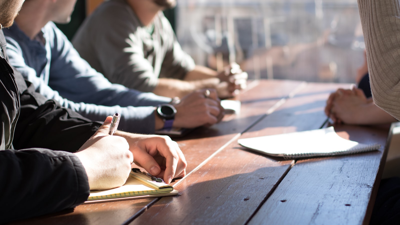People sitting on chair in front of table while holding pens during daytime — photo by Dylan Gillis on Unsplash