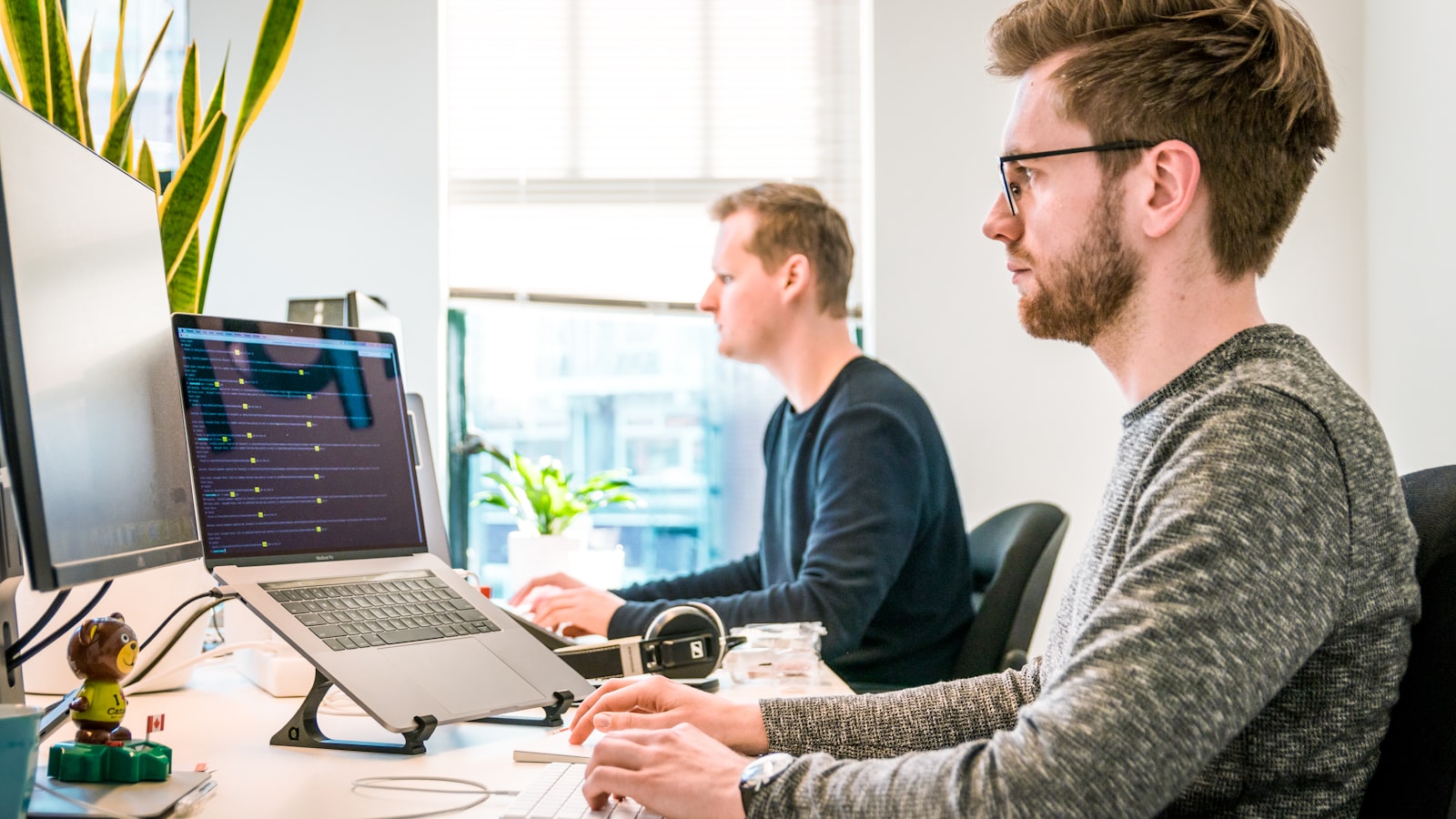 Man sitting on chair wearing gray crew-neck long-sleeved shirt using Apple Magic Keyboard — photo by Tim van der Kuip on Unsplash