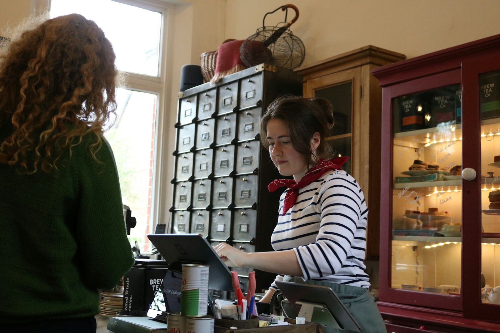 A cashier serves a customer at a shop counter. — photo by Caden Norcott on Unsplash