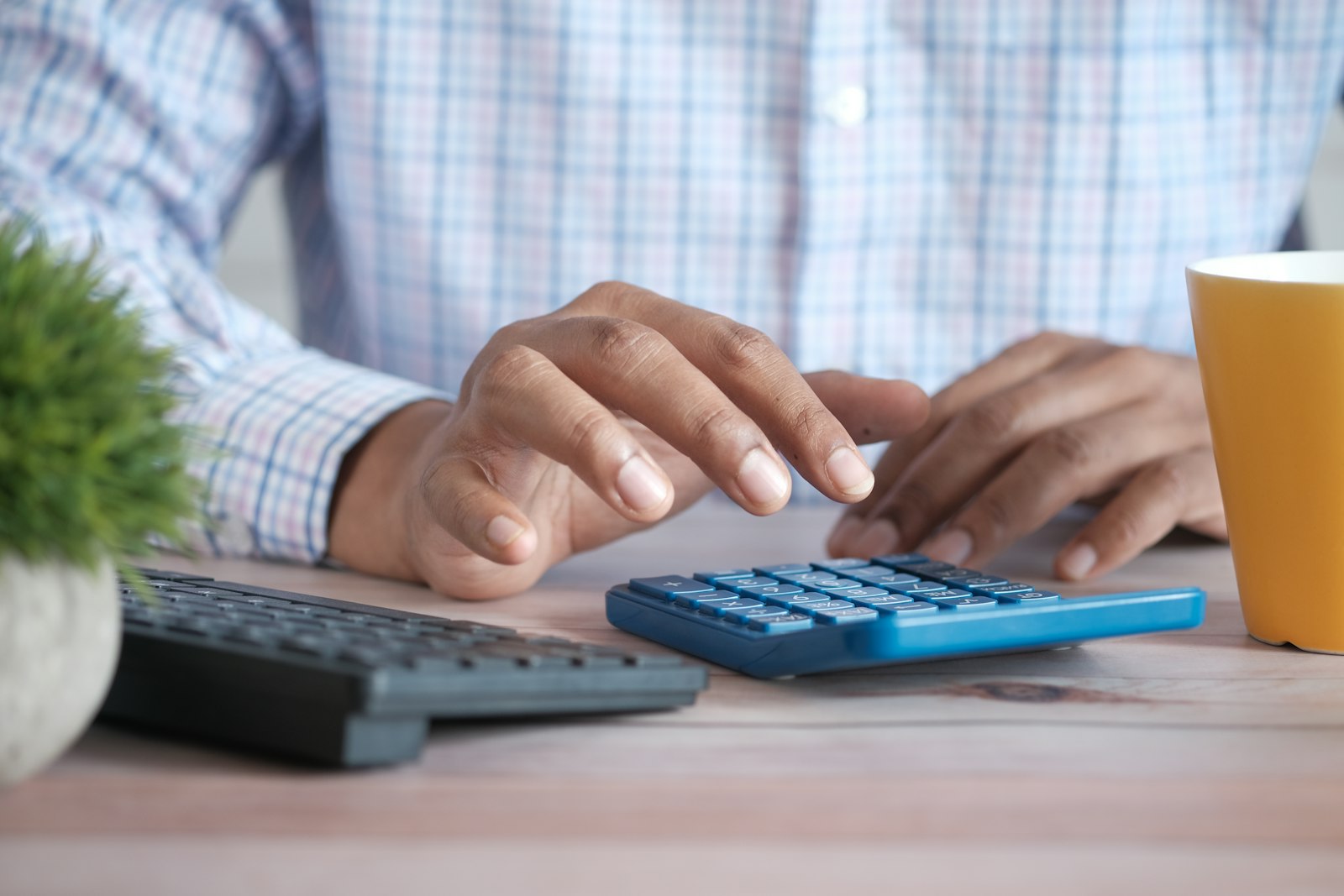 Person using calculator at desk with coffee mug — photo by Towfiqu barbhuiya on Unsplash